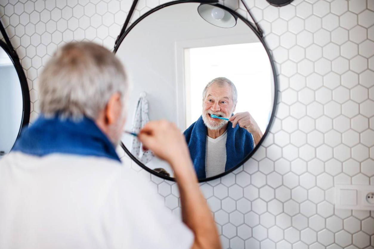 Older man trying to keep dental implants clean