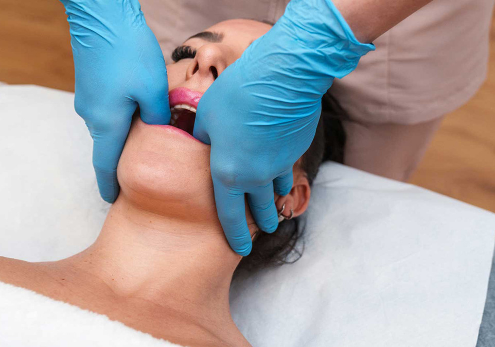 Image of dentist testing female patient's mouth by widely opening it with his hands