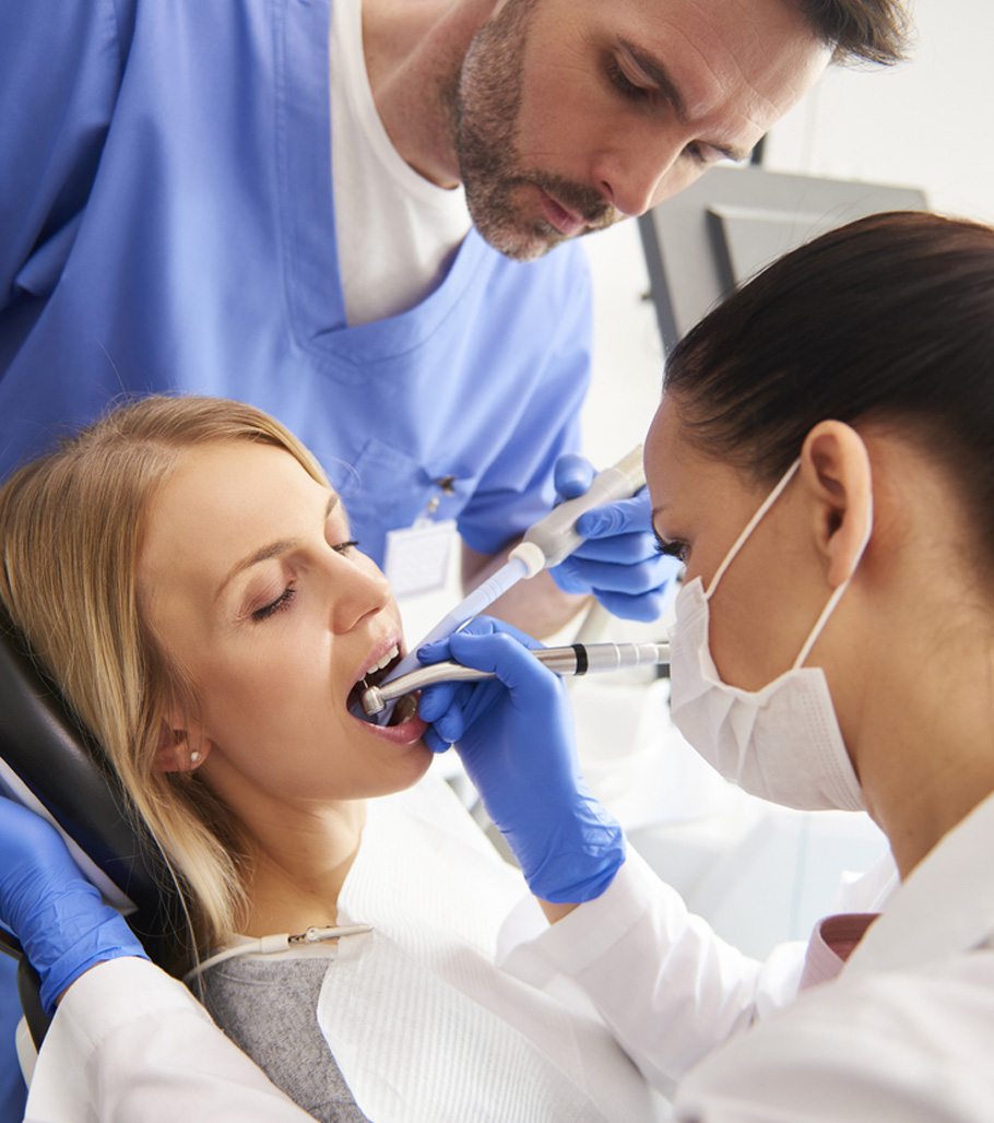 Picture of a female patient being treated by female dentist and a male assistant