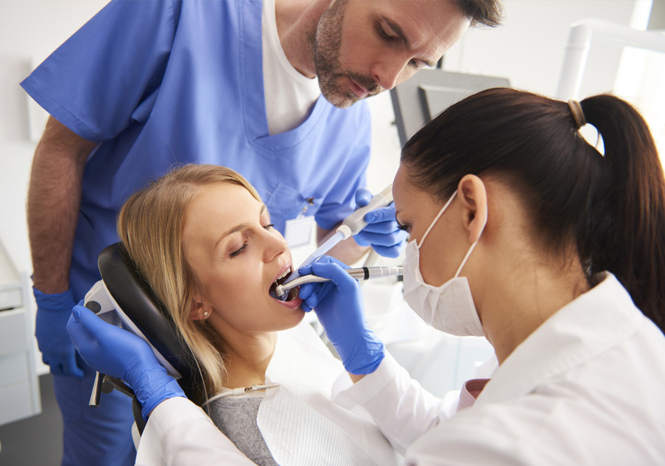 Picture of a female patient being treated by female dentist and a male assistant