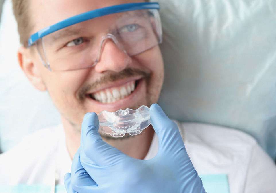 Picture of a smiling male patient being inserted a sports mouth guard by dentist