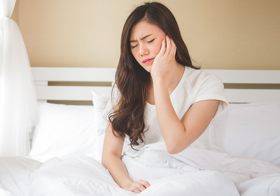 Stock image of a girl touching left side of her face and feeling tooth pain